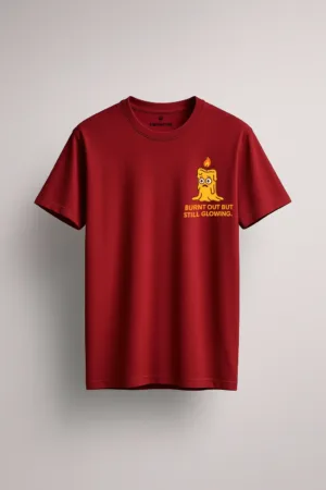 Maroon unisex t-shirt with a funny “Burnt Out But Still Glowing” quote and melting candle cartoon graphic – relatable burnout humor tee by Swankyss front view