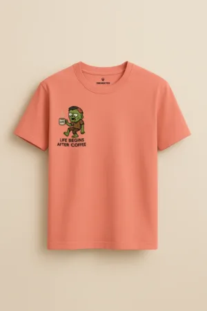 Peach unisex t-shirt with cartoon zombie and steaming cup of coffee, featuring the text “Life Begins After Coffee” – funny caffeine humor tee by Swankyss front view